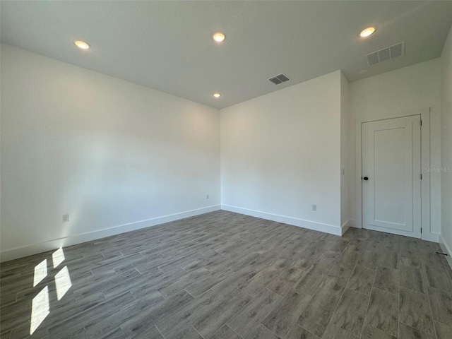 unfurnished room with recessed lighting, wood finished floors, visible vents, and baseboards