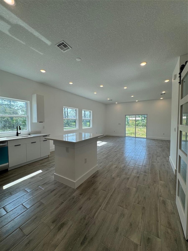 kitchen with modern cabinets, wood finished floors, a center island, light countertops, and white cabinetry