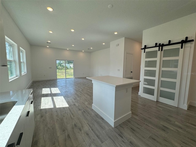 kitchen with white cabinets, light countertops, a kitchen island, and a barn door