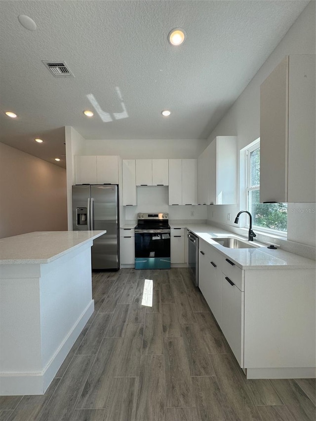 kitchen featuring white cabinetry, stainless steel appliances, a sink, and light countertops