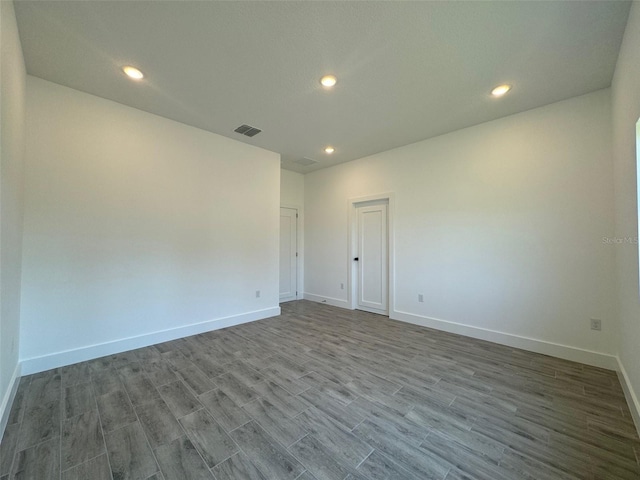 spare room featuring recessed lighting, wood finished floors, visible vents, and baseboards