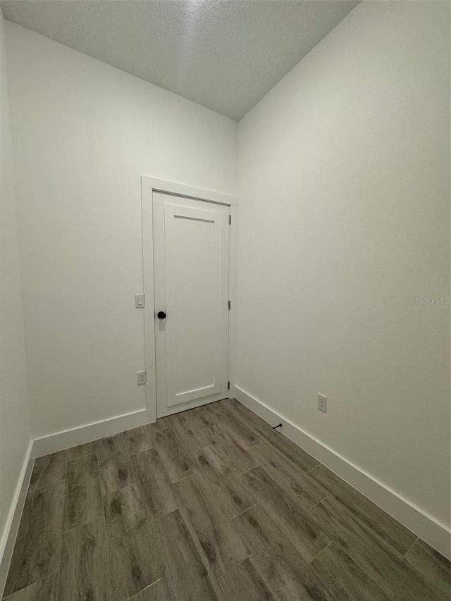 unfurnished room with baseboards and dark wood finished floors