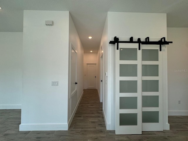 hall featuring recessed lighting, wood tiled floor, baseboards, and a barn door