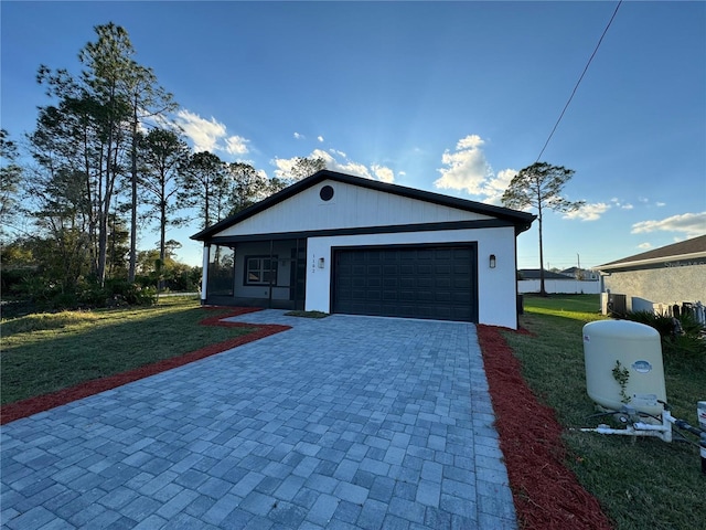 view of front of house with decorative driveway, an attached garage, and a front lawn