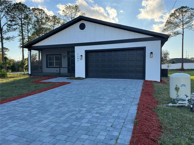 view of front of home featuring an attached garage, a front lawn, and decorative driveway