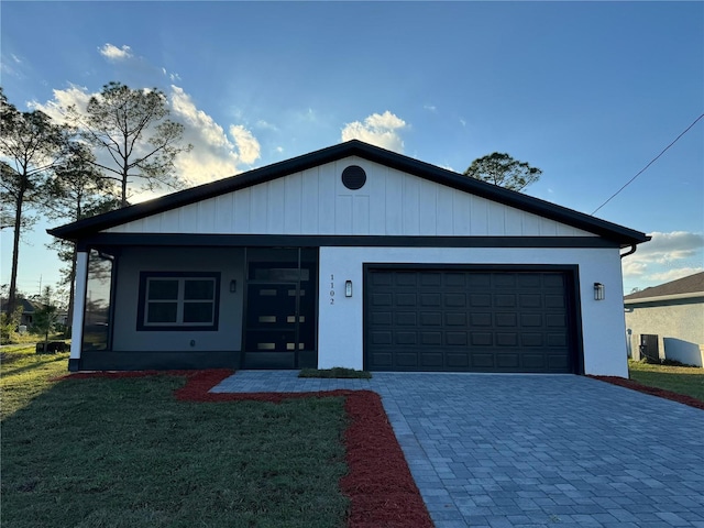 ranch-style house featuring an attached garage, decorative driveway, and a front yard