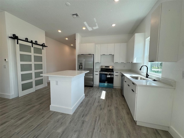 kitchen featuring light countertops, visible vents, a barn door, appliances with stainless steel finishes, and white cabinets