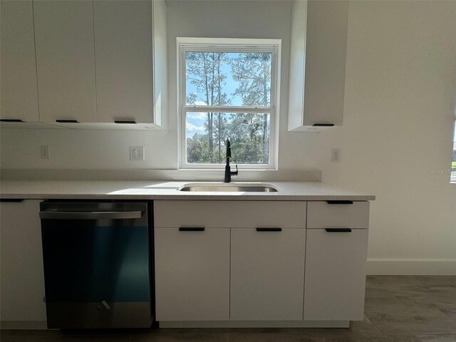 kitchen with white cabinets, light countertops, dishwasher, and a sink