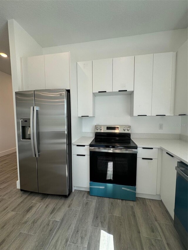 kitchen featuring electric range oven, light countertops, stainless steel refrigerator with ice dispenser, and white cabinetry