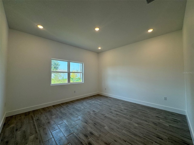 empty room with baseboards, dark wood finished floors, and recessed lighting