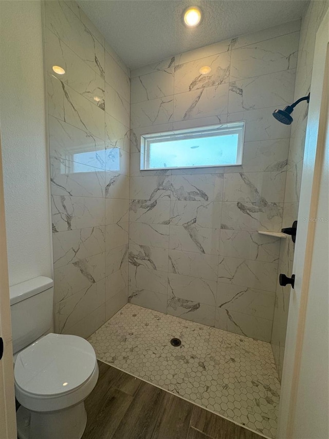 full bathroom with a textured ceiling, a stall shower, wood finished floors, and toilet