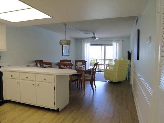 kitchen featuring hanging light fixtures, white cabinetry, light hardwood / wood-style floors, and kitchen peninsula