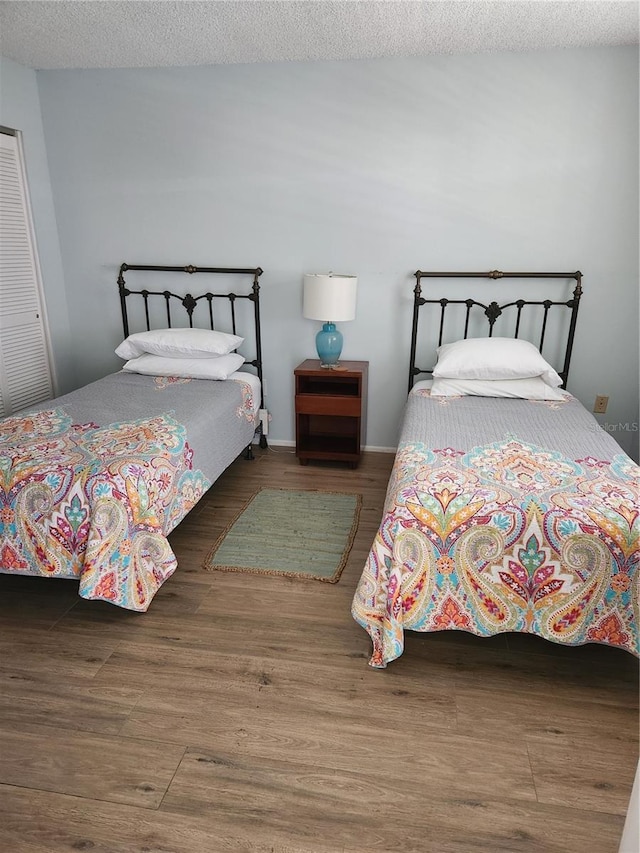 bedroom featuring a textured ceiling, baseboards, and wood finished floors