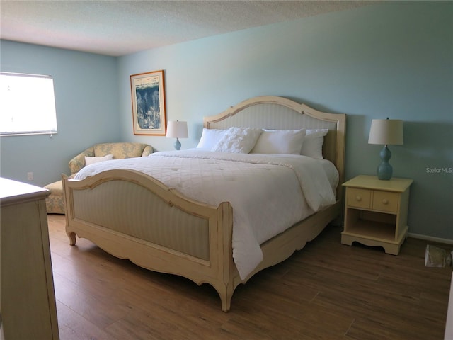 bedroom with a textured ceiling and dark hardwood / wood-style flooring