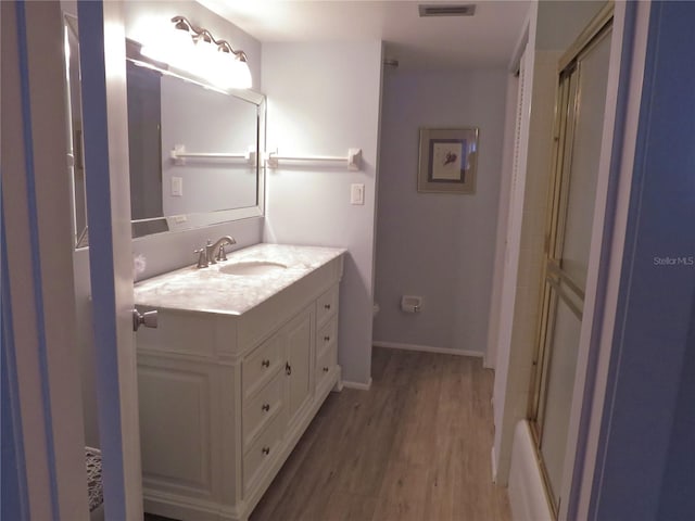 full bath with visible vents, an enclosed shower, vanity, wood finished floors, and baseboards