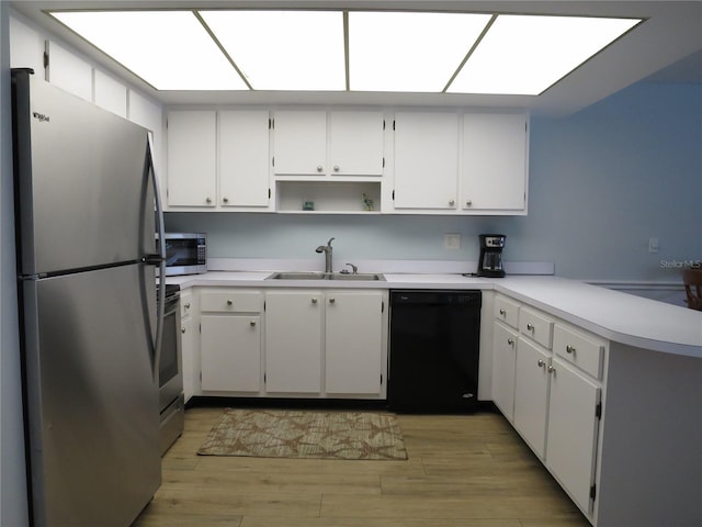 kitchen featuring stainless steel appliances, light wood-type flooring, a peninsula, and a sink