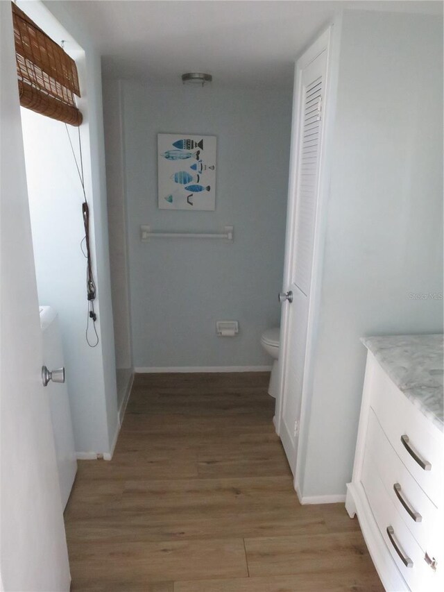 corridor featuring light wood-style flooring and baseboards