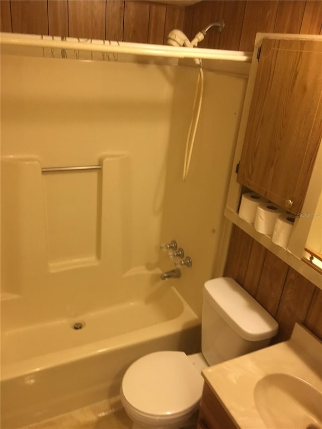 full bathroom with shower / bathtub combination, toilet, vanity, and wooden walls