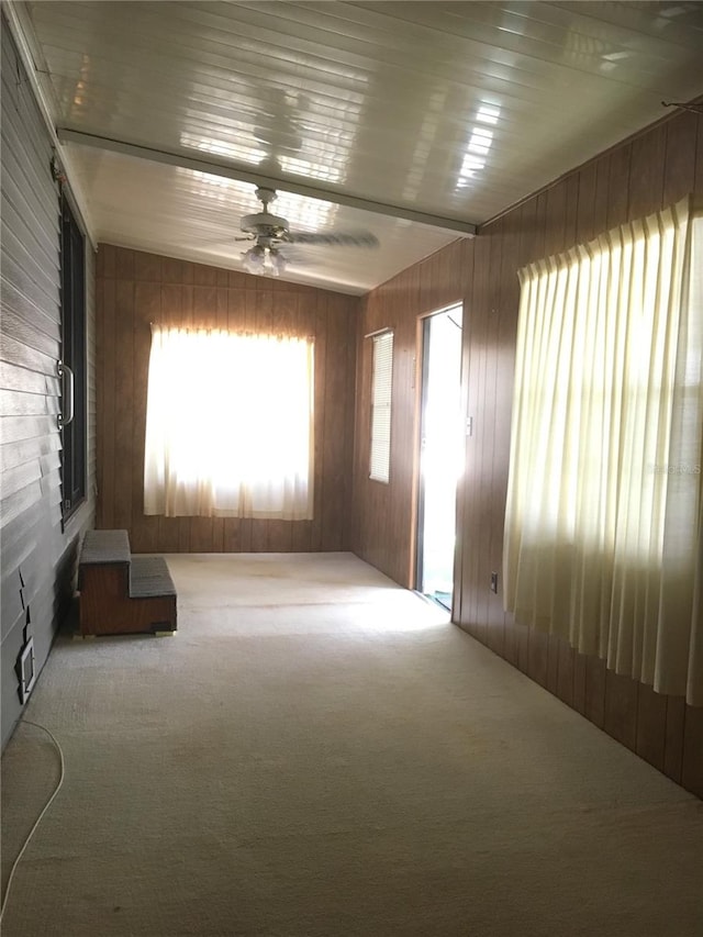 carpeted empty room featuring wood walls and ceiling fan