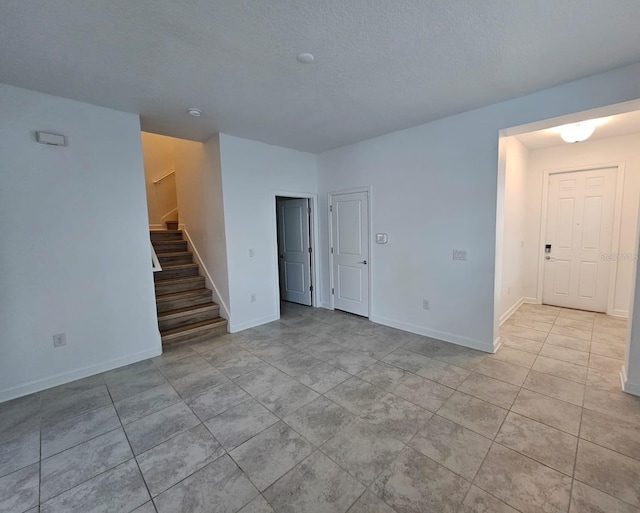 empty room featuring a textured ceiling and light tile patterned floors