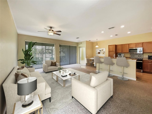 living room with light carpet, ceiling fan, and sink