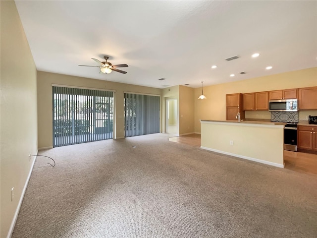 kitchen with sink, pendant lighting, backsplash, light colored carpet, and ceiling fan