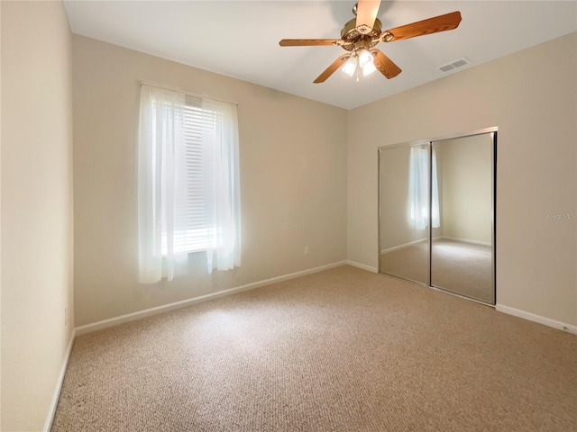 interior space featuring carpet flooring, multiple windows, a closet, and ceiling fan