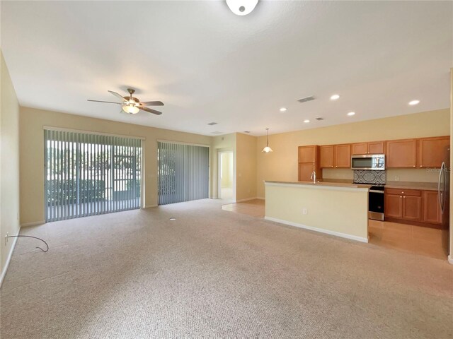 unfurnished living room with sink, light colored carpet, and ceiling fan