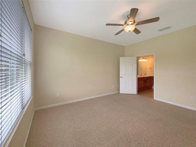 unfurnished bedroom featuring light carpet, ensuite bathroom, and ceiling fan