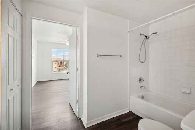 bathroom featuring tiled shower / bath combo, toilet, a textured ceiling, and hardwood / wood-style flooring