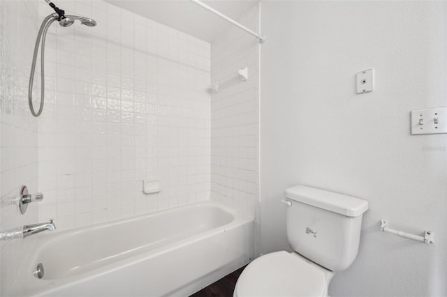 bathroom with toilet and tiled shower / bath