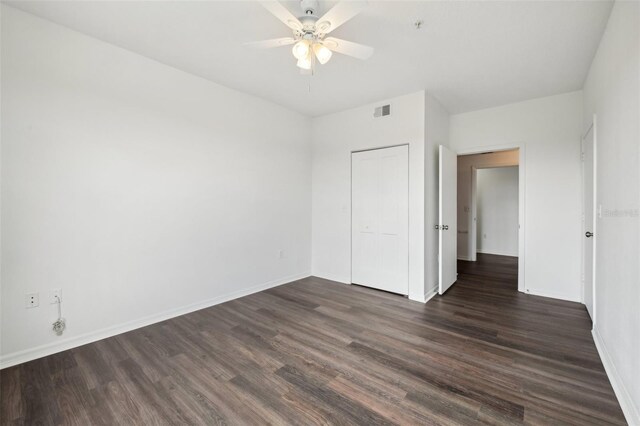 unfurnished bedroom with dark hardwood / wood-style floors, a closet, and ceiling fan