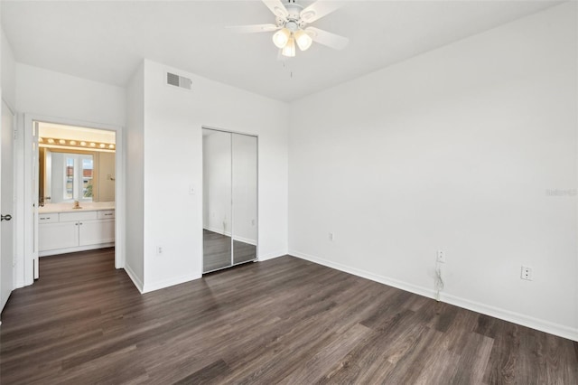 unfurnished bedroom with hardwood / wood-style flooring, a closet, ensuite bath, and ceiling fan