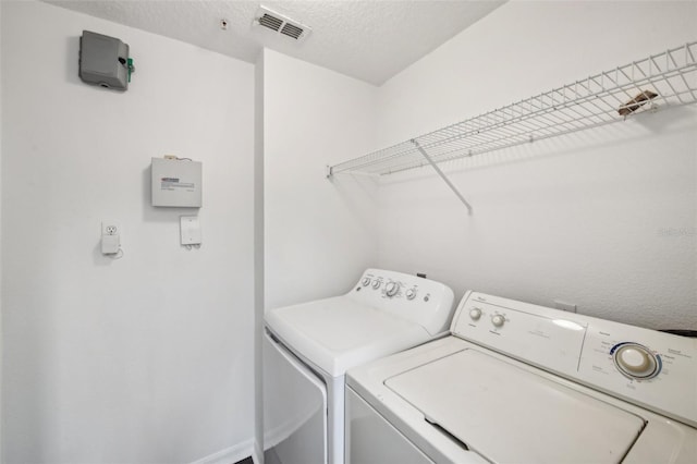 clothes washing area featuring separate washer and dryer and a textured ceiling