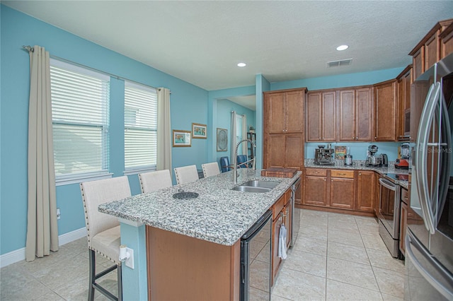 kitchen with appliances with stainless steel finishes, sink, light tile patterned floors, an island with sink, and wine cooler