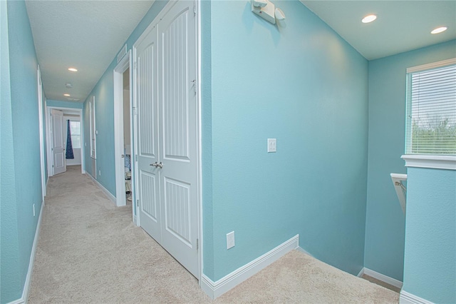 corridor with light carpet and a healthy amount of sunlight