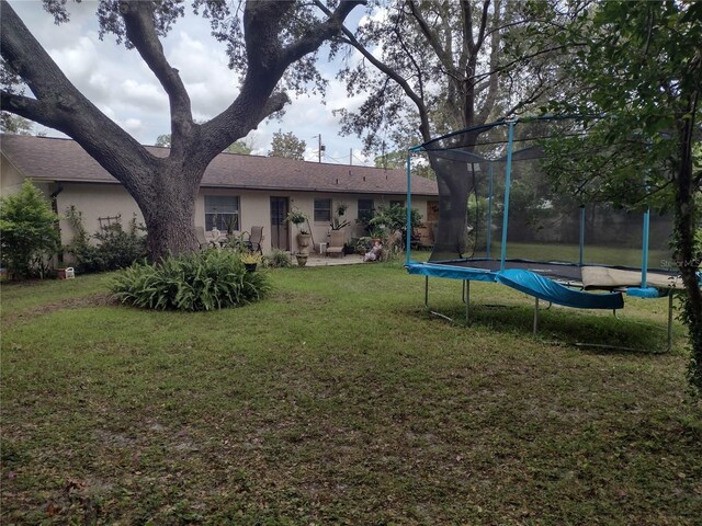 view of yard with a trampoline and a patio area