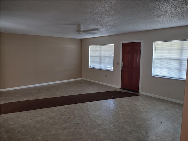 foyer entrance with a textured ceiling, a wealth of natural light, and ceiling fan