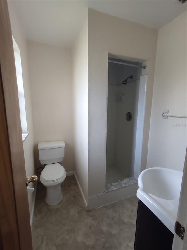 bathroom featuring vanity, toilet, and a tile shower