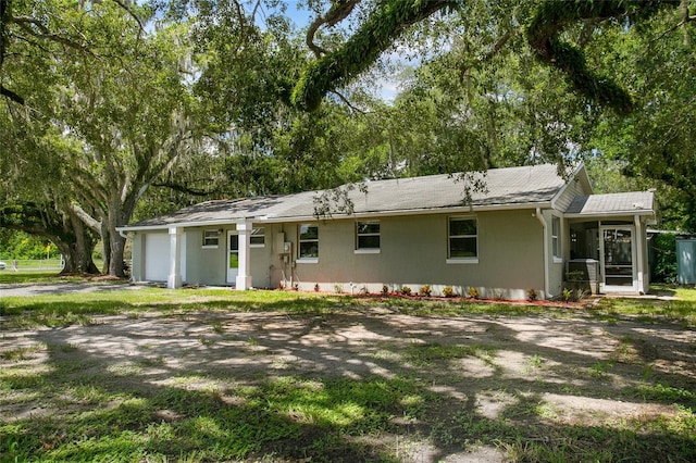 ranch-style home featuring an attached garage, a sunroom, and stucco siding