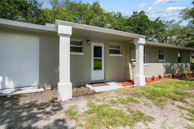 view of exterior entry with an attached garage and stucco siding