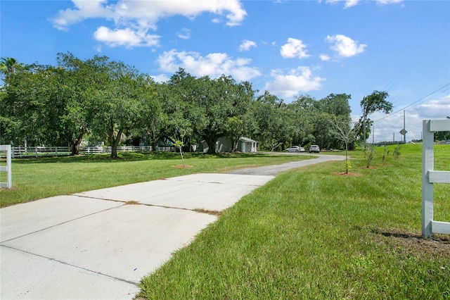 view of home's community with a yard, driveway, and fence