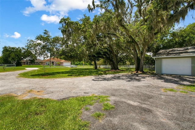 view of yard with a garage, fence, and driveway