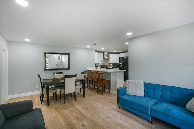 living area featuring recessed lighting, light wood-style flooring, baseboards, and a textured ceiling