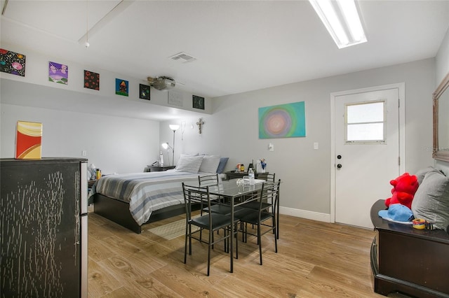 bedroom featuring light wood-style floors, attic access, visible vents, and baseboards