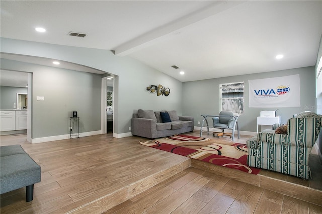 living room featuring light wood-style floors, visible vents, lofted ceiling with beams, and baseboards