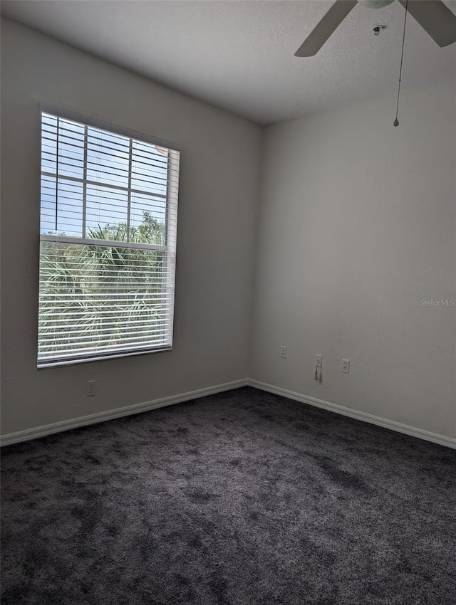 empty room featuring dark carpet and ceiling fan