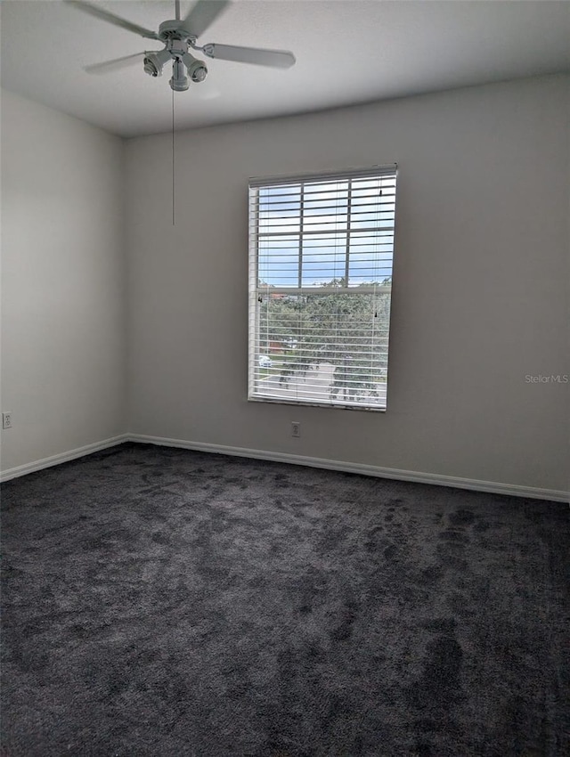 spare room with dark colored carpet and ceiling fan