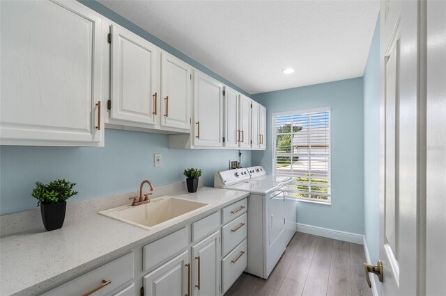 washroom with cabinets, light hardwood / wood-style flooring, sink, and independent washer and dryer