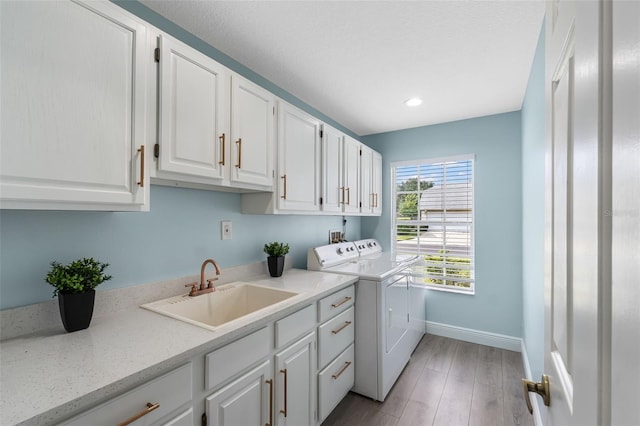 washroom with light hardwood / wood-style flooring, sink, washer and clothes dryer, and cabinets